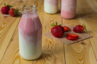 Ahşap masa üzerinde şişelerde çilek ile güler yüzlü