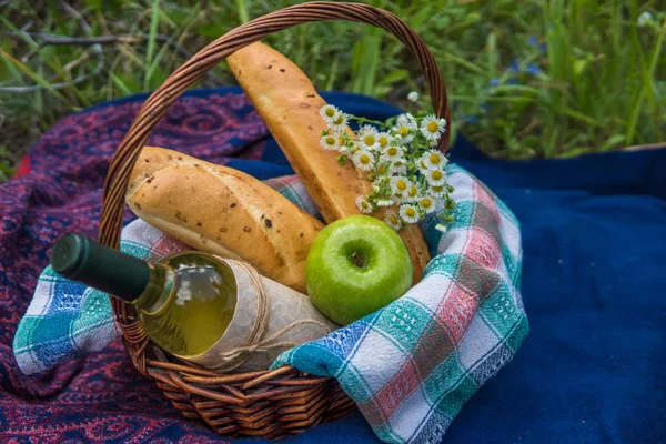 Корзина для пикника с белым вином, двумя багетами, зеленым яблоком и — стоковое фото