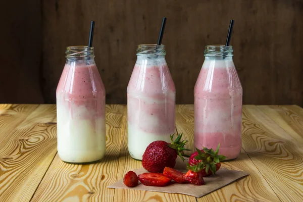 Ahşap masa üzerinde şişelerde çilek ile güler yüzlü