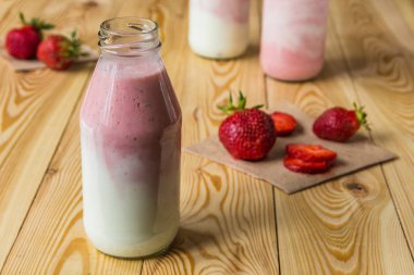 Ahşap masa üzerinde şişelerde çilek ile güler yüzlü