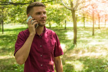 Cep telefonu parkta konuşan adam. Genç çekici adam w