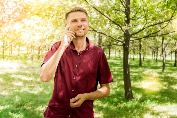 Homem com telefone móvel no parque de verão. Jovem homem bonito com sm — Fotografia de Stock