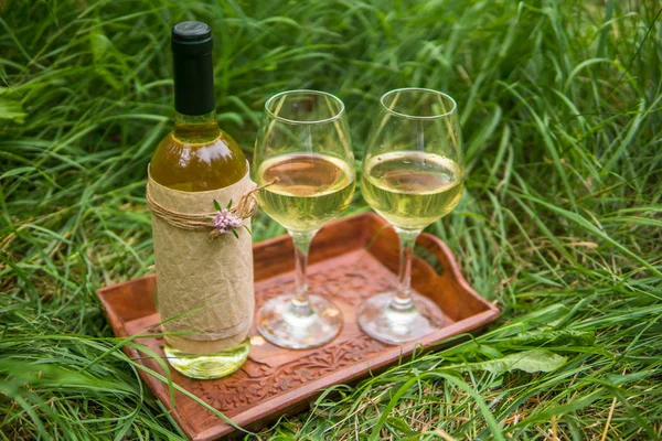 Белое вино в бутылке и бокалы для вина на деревянном спасателе — стоковое фото