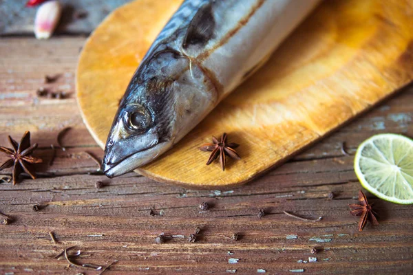 Fresh mackerel on the wooden board with slice of lime and chilli — Stock Photo, Image