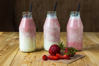 Ahşap masa üzerinde şişelerde çilek ile güler yüzlü