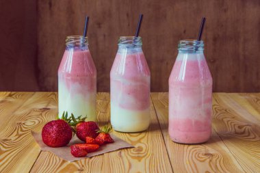 Ahşap masa üzerinde şişelerde çilek ile güler yüzlü