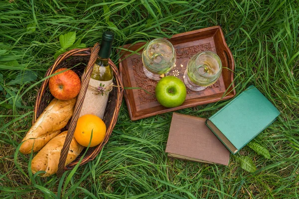 Piknik sepeti yemek, şarap ve yeşil çimenlerin üzerinde kitaplar