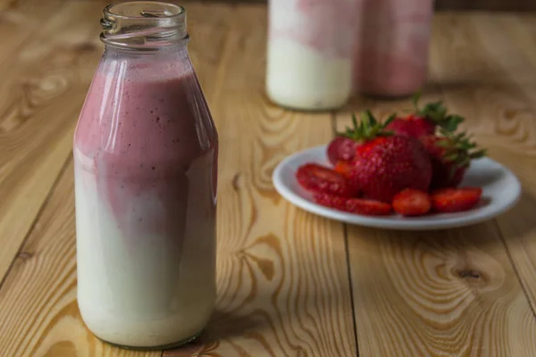 Smoothie à la fraise en bouteilles sur table en bois — Photo