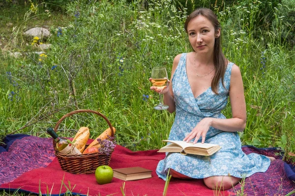 Young woman in romantic blue dress at a picnic. Girl is reading — Stock Photo, Image