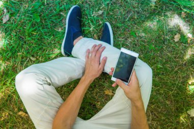 Bacaklar ve cep telefonu üst görüntüleyin. Onun smartphone oturan adam 