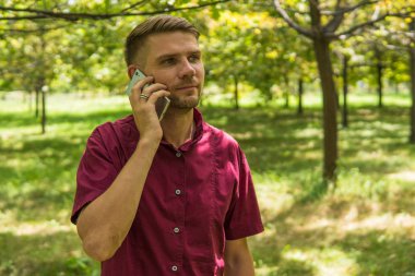 Cep telefonu parkta konuşan adam. Genç çekici adam w