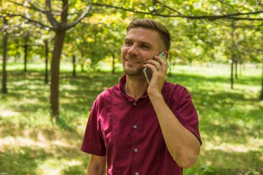 Cep telefonu parkta konuşan adam. Genç çekici adam w
