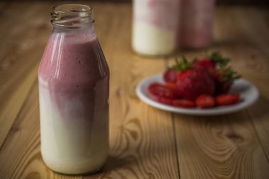 Ahşap masa üzerinde şişelerde çilek ile güler yüzlü