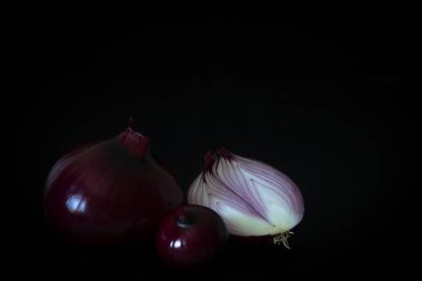 Kırmızı soğan karanlığın içinde. Siyah arka plan üzerine soğan. Minimalizm