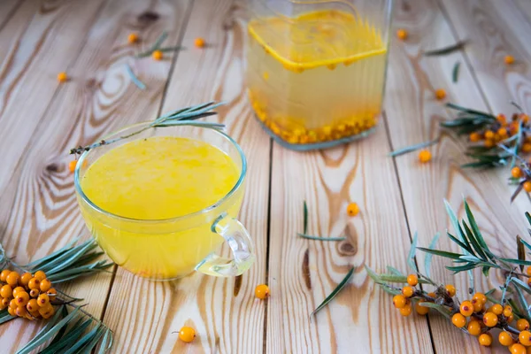 Thé avec des baies d'argousier orange dans une tasse en verre . — Photo