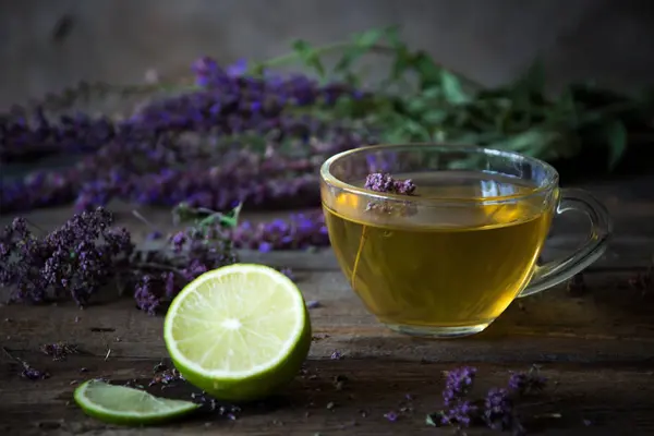 Bitkiler ve kireç ile yeşil çay. Ahşap üzerine kekik çayı 