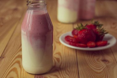 Ahşap masa üzerinde şişelerde çilek ile güler yüzlü