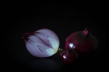 Kırmızı soğan karanlığın içinde. Siyah arka plan üzerine soğan. Minimalizm