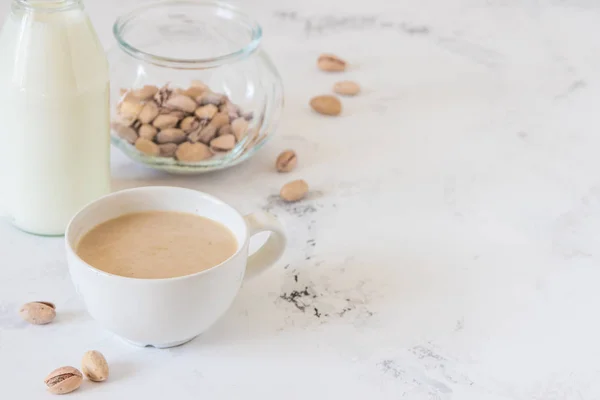 Café con leche y pistachos sobre mesa de madera, espacio para copiar — Foto de Stock