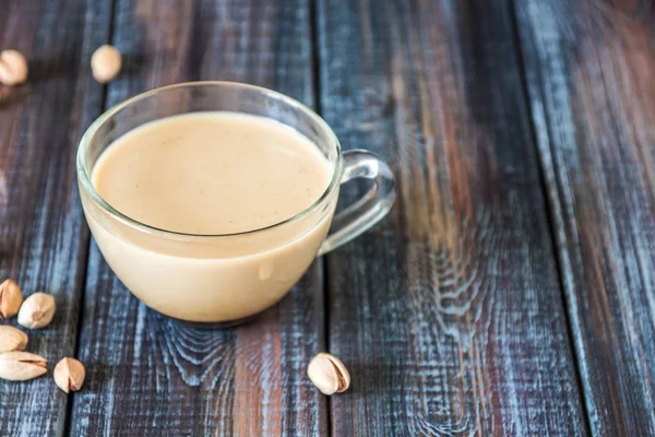 Kaffee mit Milch und Pistazien auf dem Tisch, Kopierraum — Stockfoto