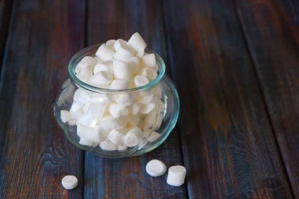 Marshmallows em um jarro de vidro em uma mesa de madeira — Fotografia de Stock