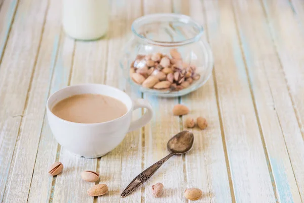 Café con leche y pistachos sobre mesa de madera — Foto de Stock