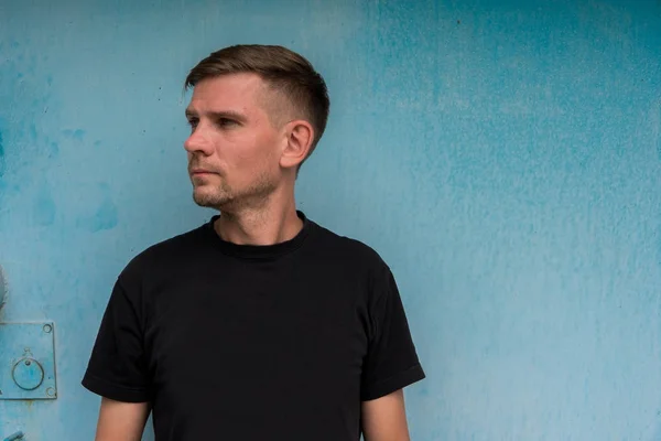 Mann in der Nähe einer blauen Metallwand. junger europäischer Mann auf der Straße — Stockfoto