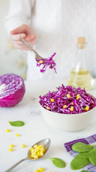 Sallad på rödkål och majs. Kvinnans hand håller gaffel med sala — Stockfoto