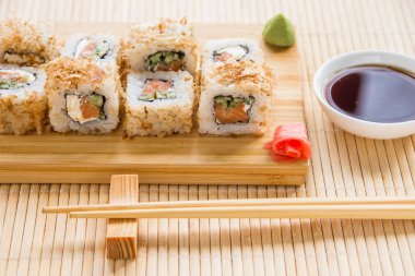 Somon, salatalık ve ton balığı deri ile suşi roll bir ahşap tahta üzerinde