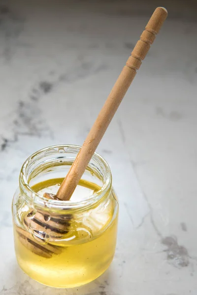 Mel em jarro com pau de madeira em uma mesa — Fotografia de Stock