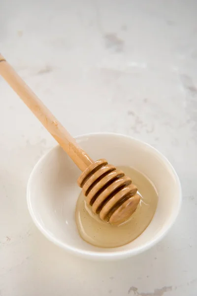 Palillo de miel en un pequeño plato blanco —  Fotos de Stock