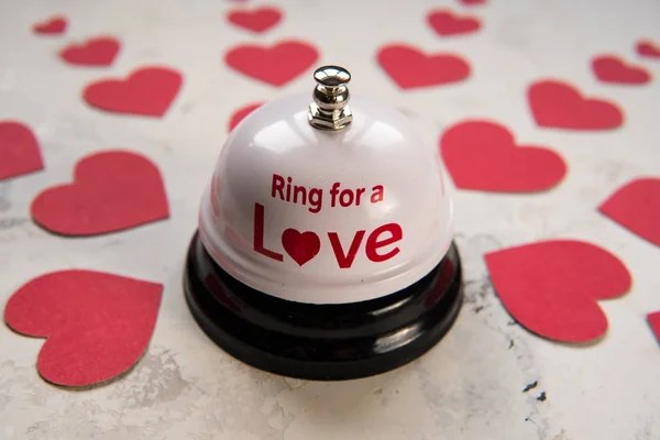 Ring bell for a love and many hearts on a wood background