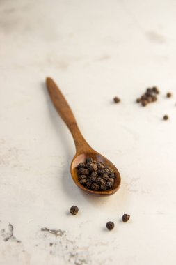 Karabiber bezelye bir tahta kaşık, açık renkli üzerinde