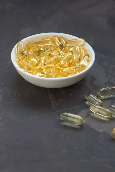 Capsule vitaminiche gialle su fondo scuro, gelatina morbida capsu — Foto Stock