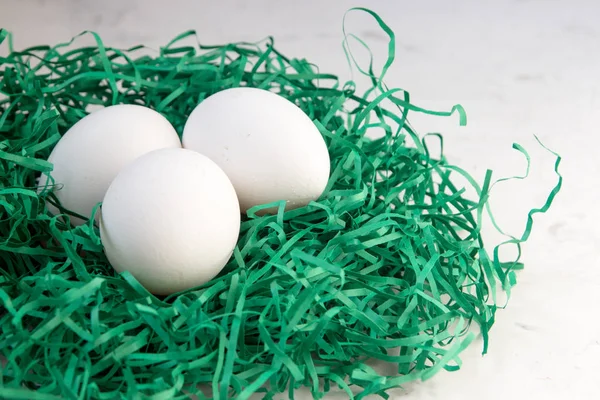 緑の紙、巣の中の卵。3 つの白い卵 — ストック写真