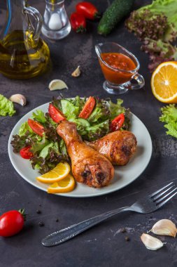 Kızarmış tavuk budu ve karanlık bir arka plan üzerinde taze salata