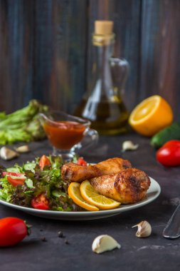 Kızarmış tavuk budu ve karanlık bir arka plan üzerinde taze salata