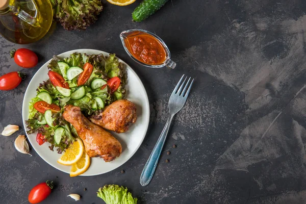 Kızarmış tavuk budu ve karanlık bir arka plan üzerinde taze salata
