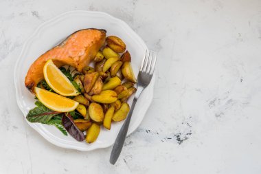 Beyaz bir plaka üzerinde balık ve yeşil salata ile kızarmış patates