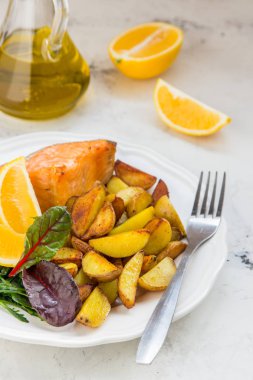 Beyaz bir plaka üzerinde balık ve yeşil salata ile kızarmış patates