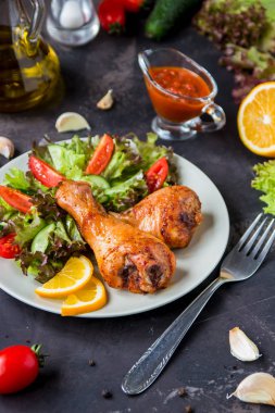 Kızarmış tavuk budu ve karanlık bir arka plan üzerinde taze salata