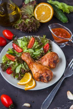 Kızarmış tavuk budu ve karanlık bir arka plan üzerinde taze salata