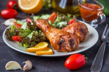 Kızarmış tavuk budu ve karanlık bir arka plan üzerinde taze salata