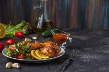 Kızarmış tavuk budu ve karanlık bir arka plan üzerinde taze salata