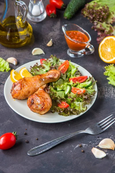 Kızarmış tavuk budu ve karanlık bir arka plan üzerinde taze salata