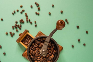 Kahve çekirdekleri bir el Kahve değirmeni bir ihale yeşil bac üzerinde