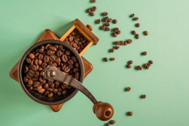 Kahve çekirdekleri bir el Kahve değirmeni bir ihale yeşil bac üzerinde