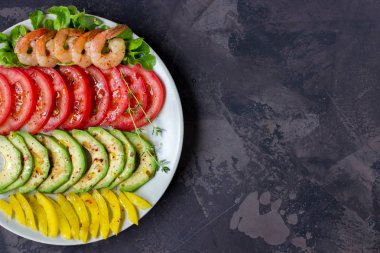 Avokado, domates, biber ve satır ile kaplı bir tabak karides. 