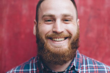 Sakallı yakışıklı genç adam gülümsüyor.