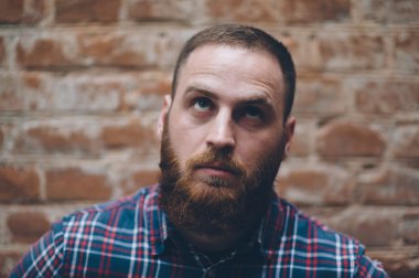 eski bir tuğla duvar çerçevede sakallı genç adam